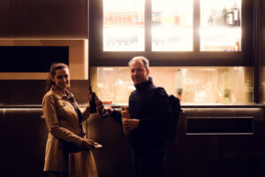 Adriana and Mario cheering with beer in front of Bitzinger Würstelstand, celebrating the vibrant atmosphere of Vienna.