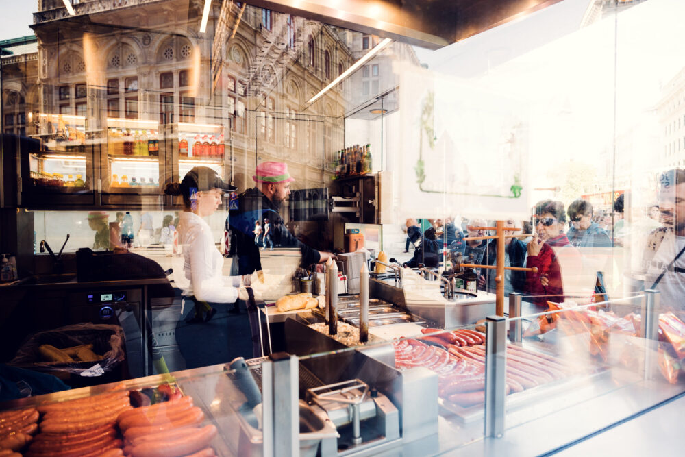 Skilled preparation of sausages at Bitzinger Würstelstand, showcasing the art of Viennese street cuisine.