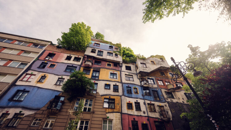 Whimsical windows of Hundertwasserhaus, each uniquely shaped and decorated, telling stories of Friedensreich Hundertwasser's artistic vision.