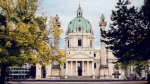 The stunning St. Charles Church (Karlskirche) in Vienna, a baroque church with a large green dome and two ornate columns on either side of its entrance.