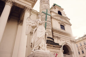 A close-up of a statue of an angel positioned in front of one of the ornate columns