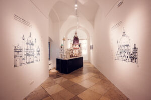 A detailed model of St. Charles Church (Karlskirche) displayed inside the church. The model showcases the intricate design of the building, including the dome, columns, and ornate interior details