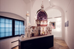 A detailed model of St. Charles Church (Karlskirche) displayed inside the church. The model showcases the intricate design of the building, including the dome, columns, and ornate interior details