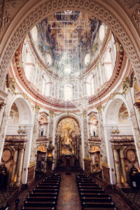 The grand interior of St. Charles Church (Karlskirche), with its impressive domed ceiling adorned with frescoes and gold detailing