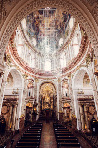 The grand interior of St. Charles Church (Karlskirche), with its impressive domed ceiling adorned with frescoes and gold detailing