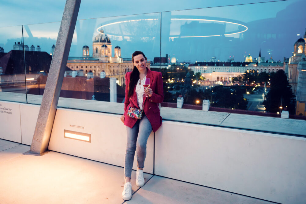 Adriana at MQ Libelle Vienna with distinctive curved glass structure.