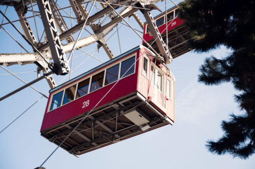 The Giant Ferris Wheel (Wiener Riesenrad) towering against cotton-candy clouds, its red cabins providing pops of color in the dreamy sky.