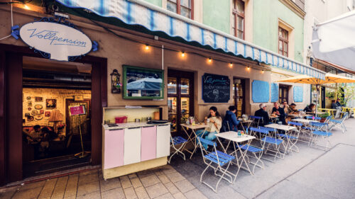 The exterior of Vollpension, featuring a colorful and inviting outdoor seating area