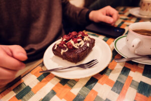 A slice of rich chocolate cake topped with cherries and almond slivers, served at Vollpension