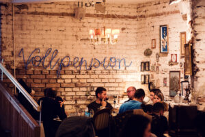 The interior of Vollpension, where people are gathered, enjoying a coffee in a cozy, rustic setting