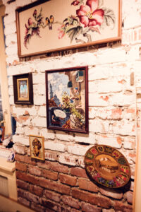 A collection of vintage-style artwork hanging on a rustic brick wall inside Vollpension