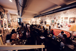 The cozy interior of Vollpension, with guests seated at various tables enjoying their food and drinks