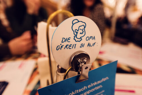 A small table sign at Vollpension with an illustration of a smiling grandma and the message, "Die Oma gfreit si auf!" ("Grandma is looking forward to seeing you!")