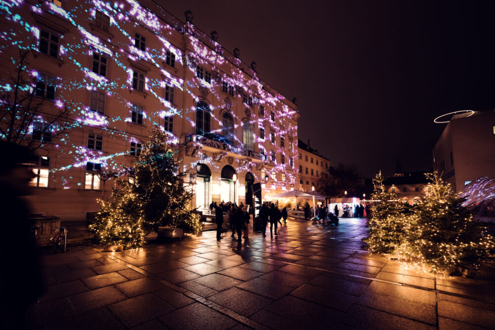 Evening atmosphere in MuseumsQuartier´s main courtyard with illuminated cultural institutions and social gatherings.
