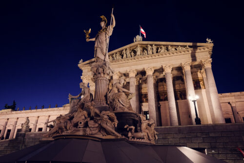 Austrian Parliament illuminated at night, showcasing its architectural beauty.