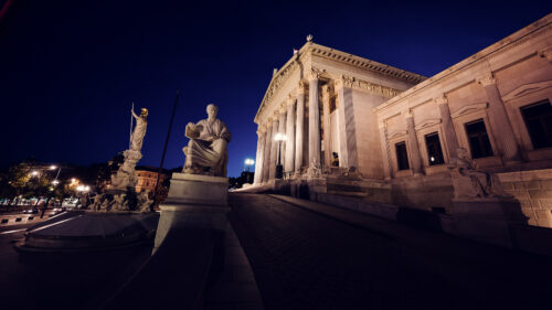 Austrian Parliament illuminated at night, showcasing its architectural beauty.