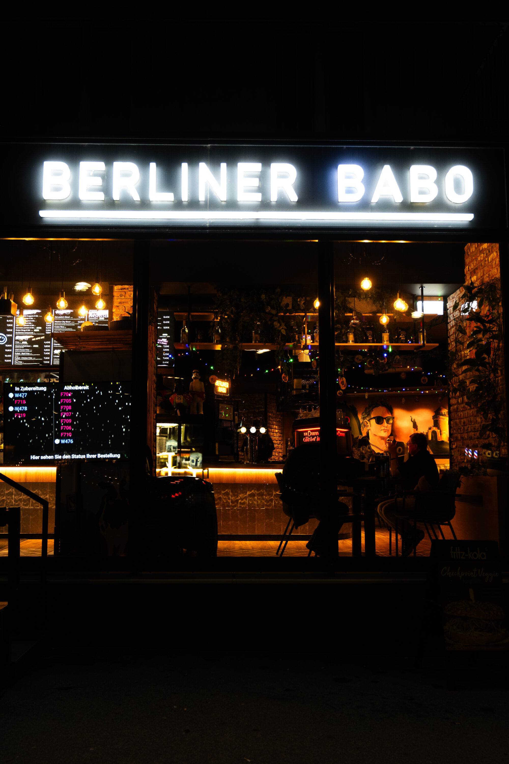 The entrance of Berliner Babo in Wien Meidling is modern and inviting, the warm interior lighting offers a glimpse into its cozy, stylish atmosphere.