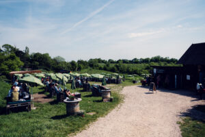 Mayer am Nussberg winery, featuring green umbrellas, rustic tables and lush vineyards in the background.