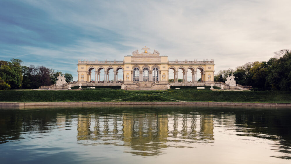 Gloriette's perfect reflection mirrored in still waters, creating a symmetrical masterpiece of baroque architecture.
