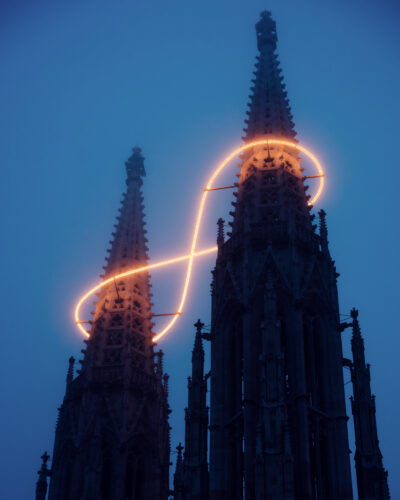 Close-up of a Votive Church spire wrapped by Infinity of Light by Billi Thanner, glowing in a warm loop.