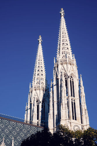 Votivkirche Vienna's neo-Gothic spires with their intricate openwork design capturing the golden summer evening light.