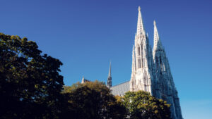 Dramatic upward view of Votivkirche Vienna's (Votive Church) twin neo-Gothic spires reaching 99 meters into the summer sky.
