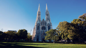 Detailed view of Votivkirche Vienna showing the intricate neo-Gothic tracery and pointed arches in bright summer light.