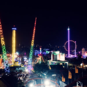 Il Prater di Vienna di notte con giostre illuminate e luci festive.