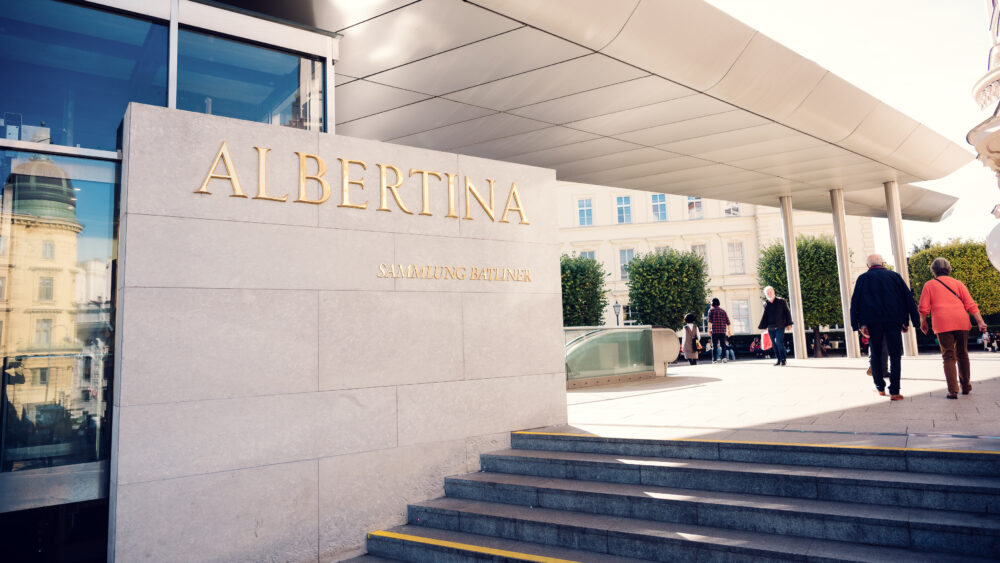 Entrance of Albertina Museum with modern architectural elements and visitors.