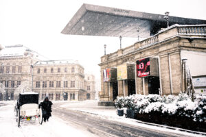 Winter view of Albertina Museum with art banners displayed on the facade in Vienna.