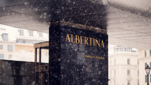 Albertina Museum sign with snow-covered exterior and historical backdrop.