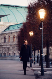 Adriana walking near Albertina Museum and its surrounding historical buildings at night.