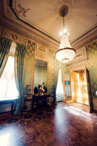 Elegant green-walled room in Albertina Museum with antique furniture and chandeliers.