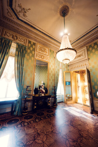 Elegant green-walled room in Albertina Museum with antique furniture and chandeliers.