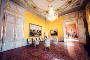 Ornate room with yellow walls and chandelier in Albertina Museum's historic section.
