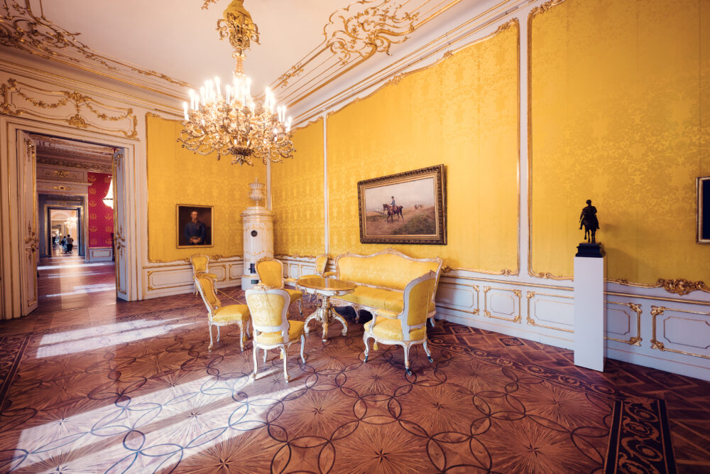 Historical yellow-themed dining room with chandelier and antique decor in Albertina Museum.