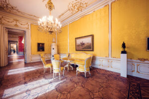 Historical yellow-themed dining room with chandelier and antique decor in Albertina Museum.