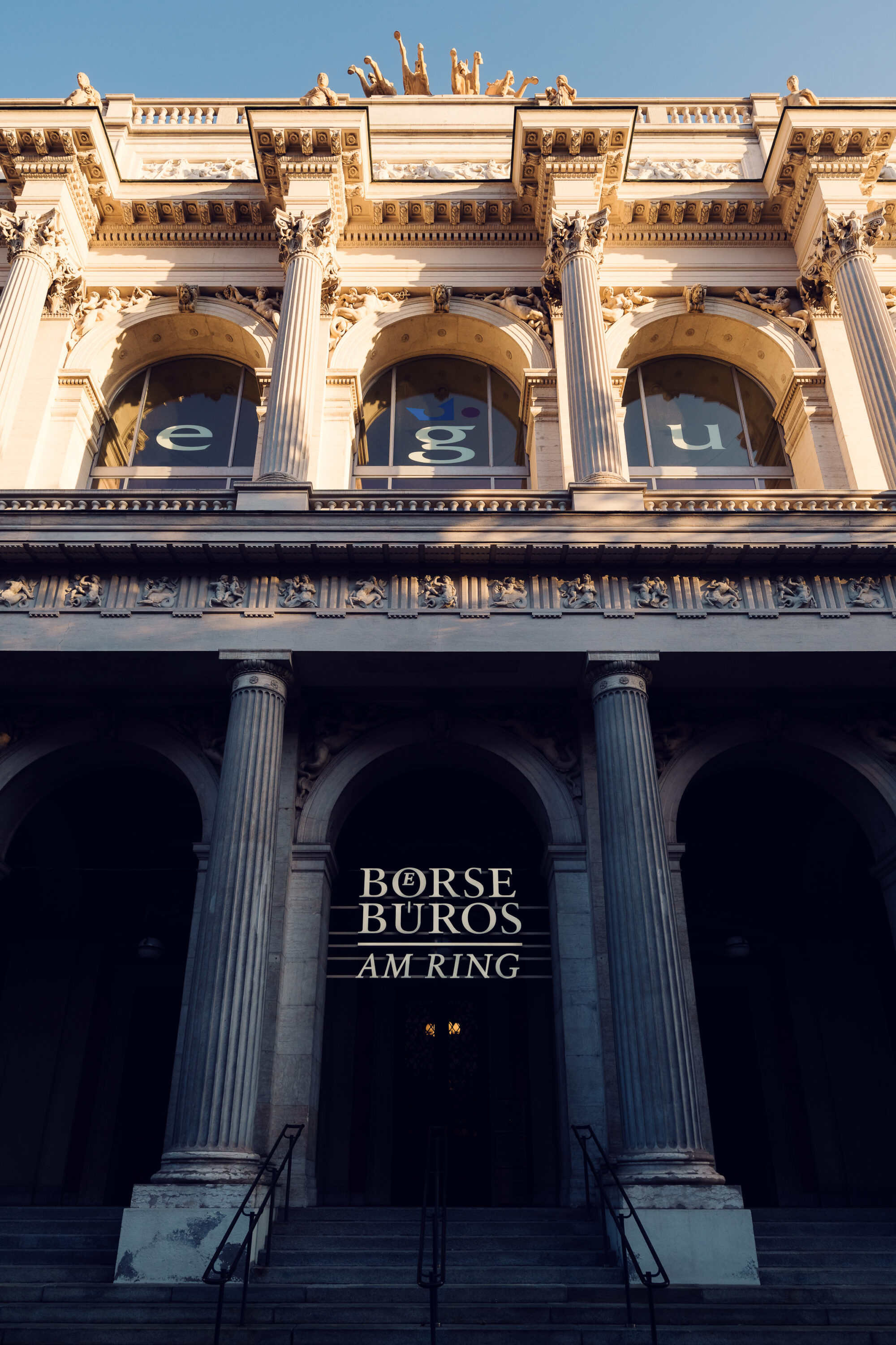 The Vienna Stock Exchange building features a grand entrance framed by towering columns and intricate architectural details, symbolizing its historical importance and stately presence along the Ringstrasse.