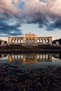 Gloriette's perfect reflection mirrored in still waters, creating a symmetrical masterpiece of baroque architecture.