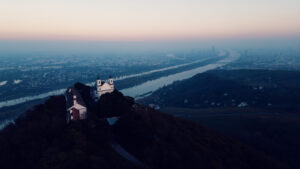 Aerial view of Leopoldsberg's baroque St. Leopold Church perched dramatically on Vienna's highest hill.