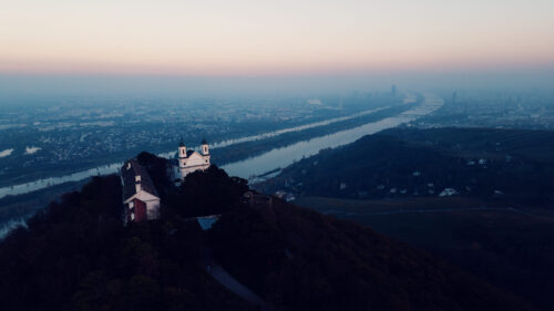 Aerial view of Leopoldsberg's baroque St. Leopold Church perched dramatically on Vienna's highest hill.