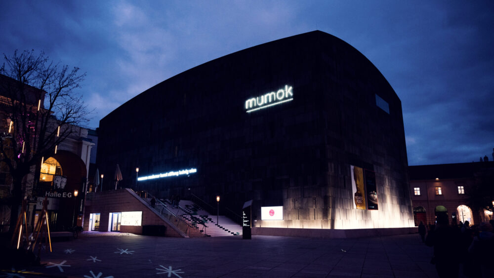 Night view of MUMOK Vienna with minimal lighting emphasizing the geometric form and volcanic stone texture of this contemporary architectural landmark.