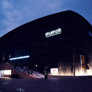 Night view of MUMOK Vienna with minimal lighting emphasizing the geometric form and volcanic stone texture of this contemporary architectural landmark.