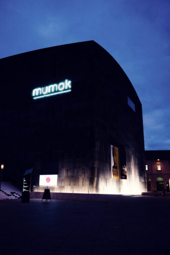 MUMOK Vienna's basalt facade at blue hour creating a striking silhouette against the deep blue evening sky over Vienna's cultural quarter.