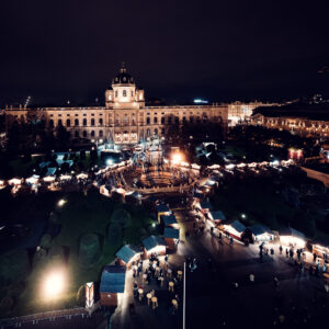 Mercatino di Natale al Maria-Theresien-Platz con bancarelle in legno, luci e decorazioni tra i due musei.