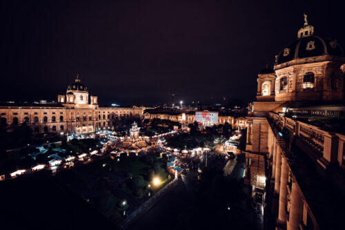 Christmas market stalls at Natural History Museum Vienna (Naturhistorisches Museum Wien), displaying traditional wooden booths with warm lighting.