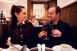 Romantic wine moment at Plachutta featuring Adriana and Mario toasting with premium Austrian Zweigelt.