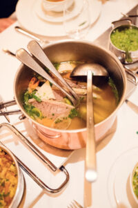 Golden soup served with root vegetables, bone marrow, and delicate herb garnish demonstrates centuries of culinary expertise at Plachutta.