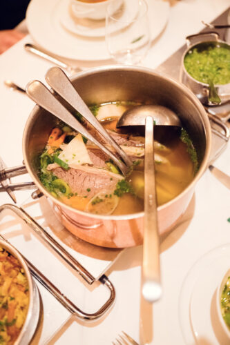 Golden soup served with root vegetables, bone marrow, and delicate herb garnish demonstrates centuries of culinary expertise at Plachutta.