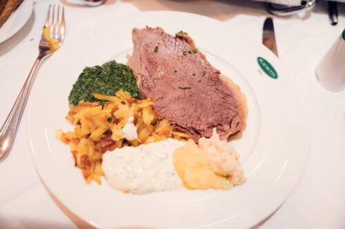 Plachutta's expertly carved Tafelspitz, showcasing tender slices of prime beef arranged with root vegetables and bone marrow.